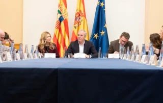Reunión institucional en Aragón sobre la implantación de la cuota cero para autónomos, con representantes del Gobierno y banderas oficiales al fondo.
