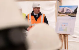 Representante del Gobierno de Aragón presentando las obras del nuevo Centro de Salud Perpetuo Socorro en Huesca, junto a los planos del proyecto.