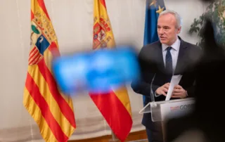 Intervención del presidente de Aragón en un acto institucional, con banderas oficiales al fondo.