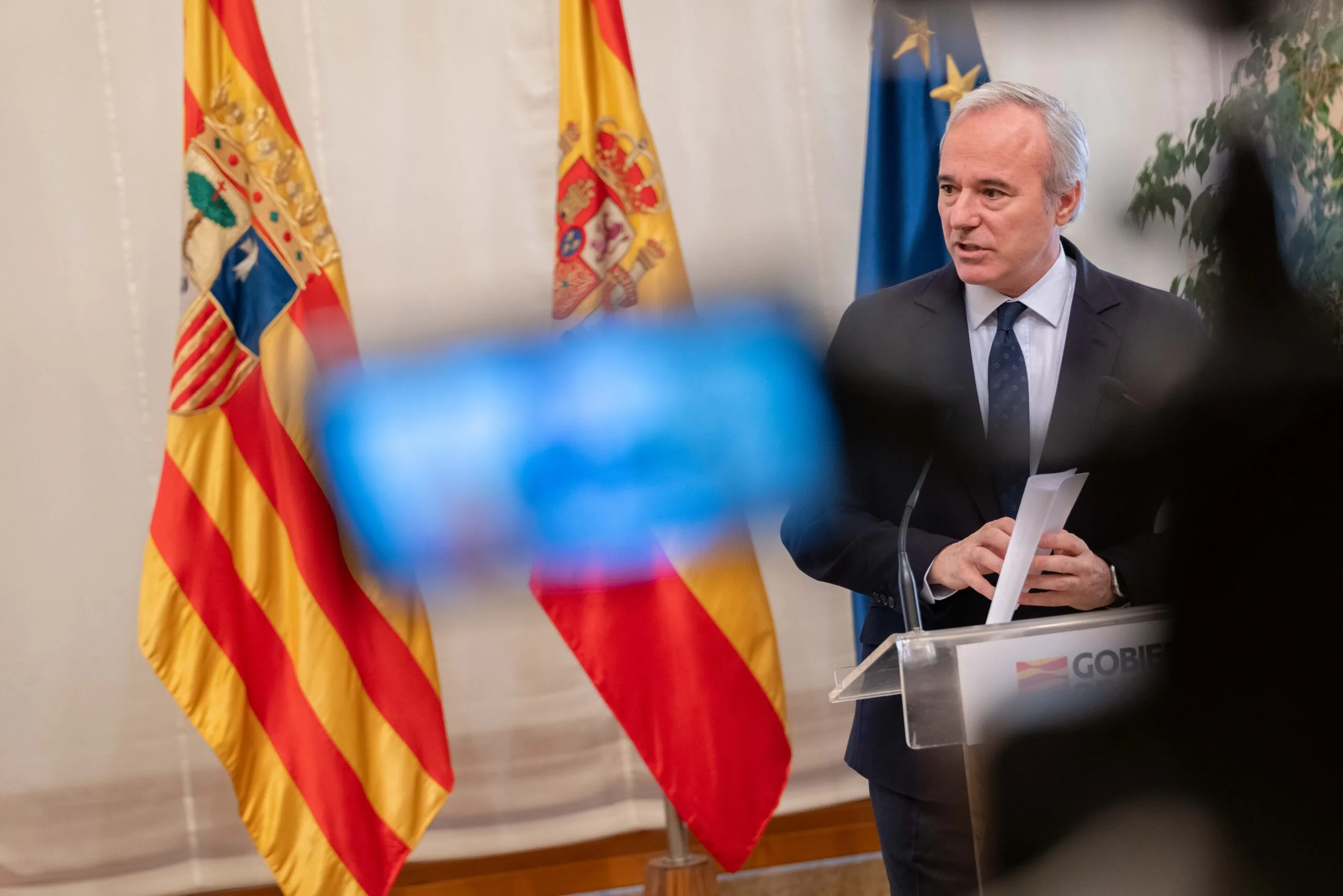 Intervención institucional del presidente de Aragón Intervención del presidente de Aragón en un acto institucional, con banderas oficiales al fondo.