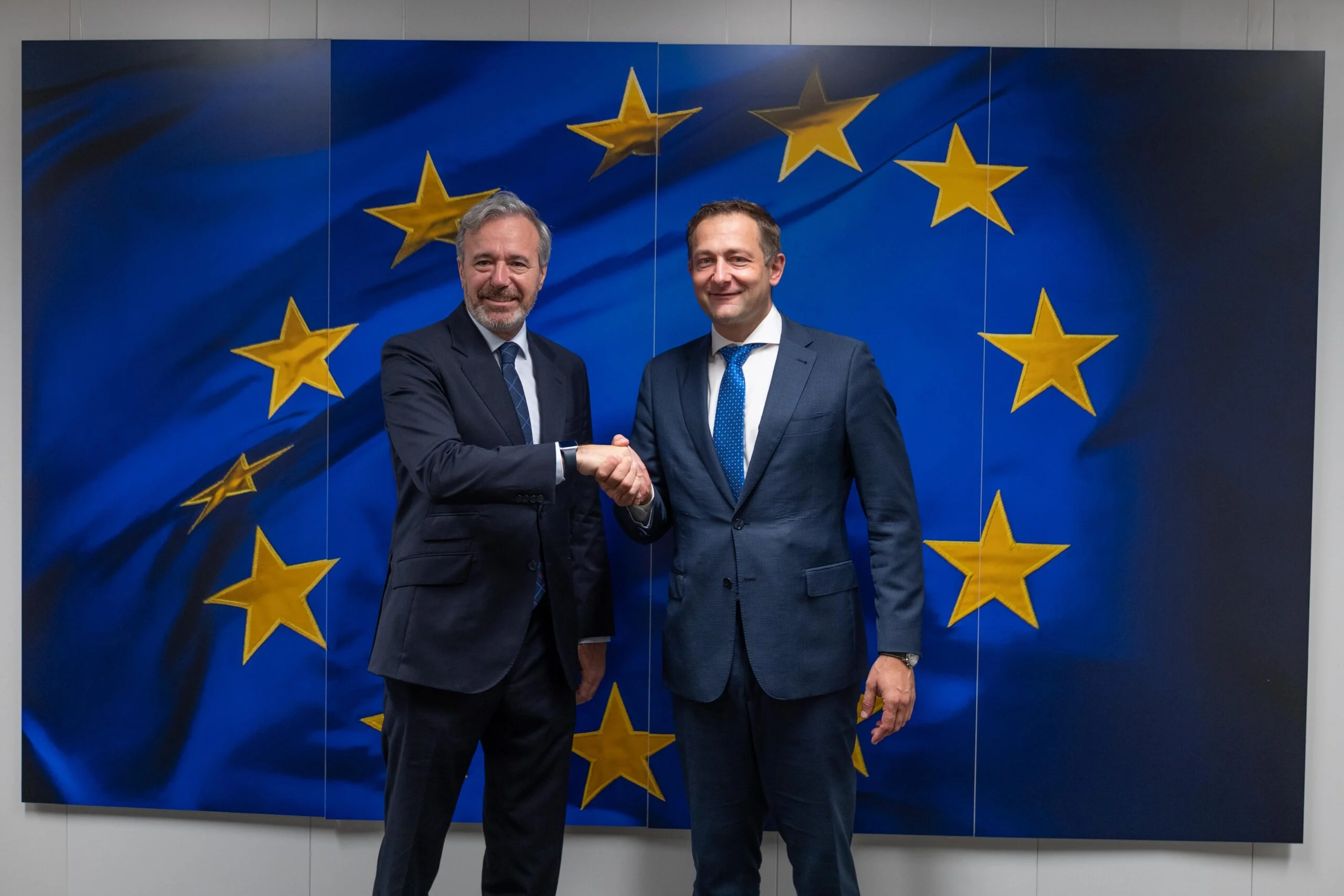 PAC justa para Aragón El presidente del Gobierno de Aragón saluda al comisario europeo de Agricultura y Alimentación ante una gran bandera de la Unión Europea durante una reunión para defender una PAC justa que tenga en cuenta la despoblación y el campo aragonés.